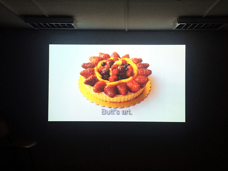 Projection of a fruit tart with a subtitle in a dark room, video what's art