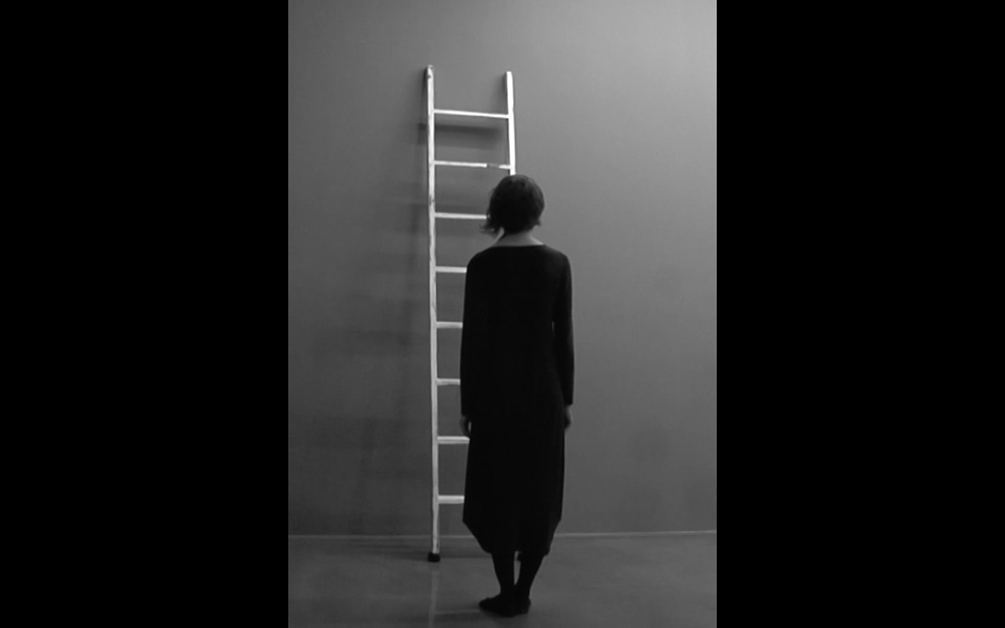Still from the video Method: a woman standing in front of a white ladder