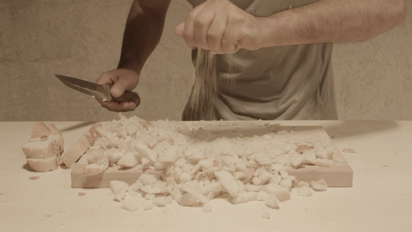 A worker's hands crumbling bread into pieces, still from I'm a flour in absence