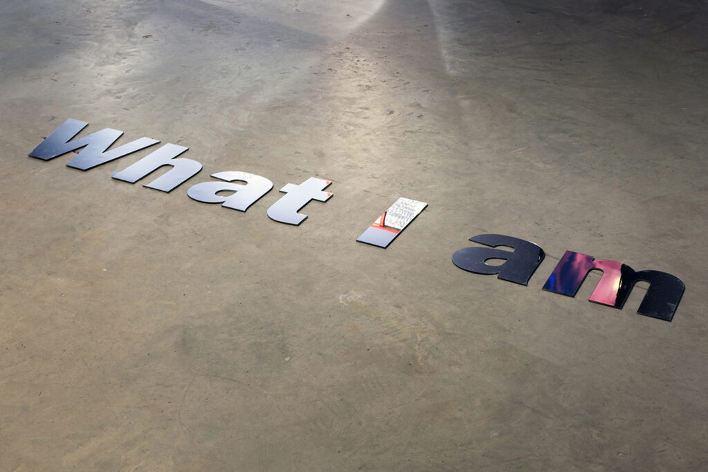 Mirrored letters spelling what I am laid on a concrete floor