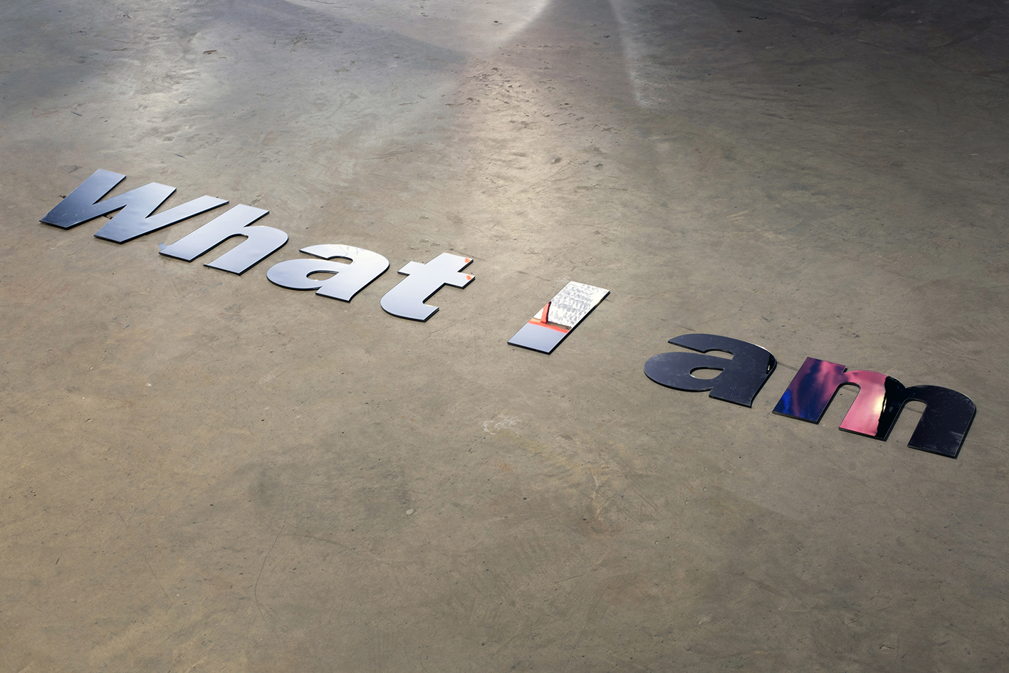 Mirrored letters spelling what I am laid on a concrete floor