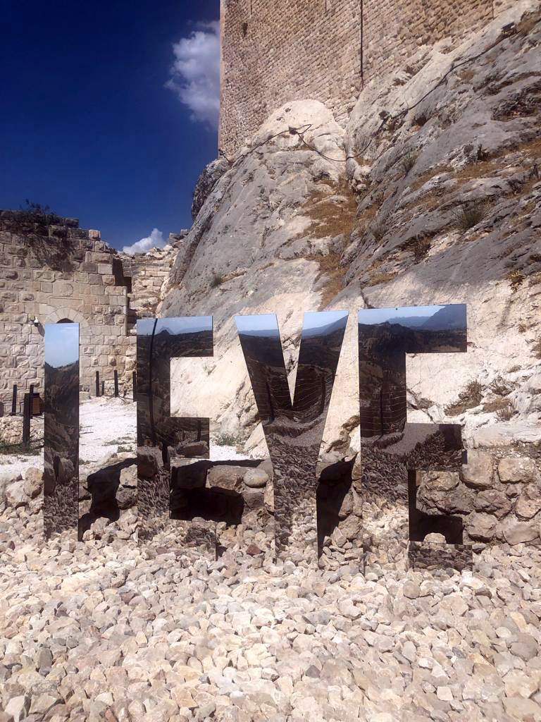 Close view of the mirrored letters I EYE among stones and ruins