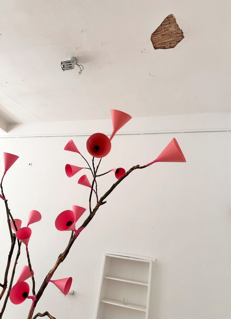 Pink cone-shaped sound elements on branches below the damaged studio ceiling at Bethanien